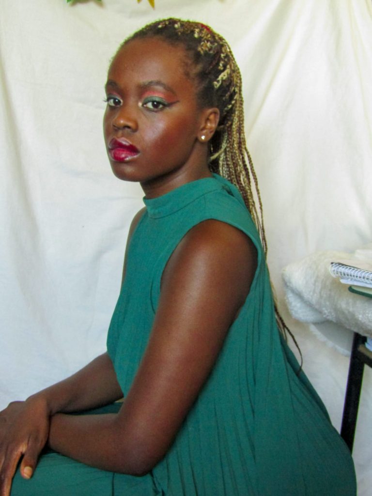 self-portrait: woman sitting staring at the camera while wearing a green dress