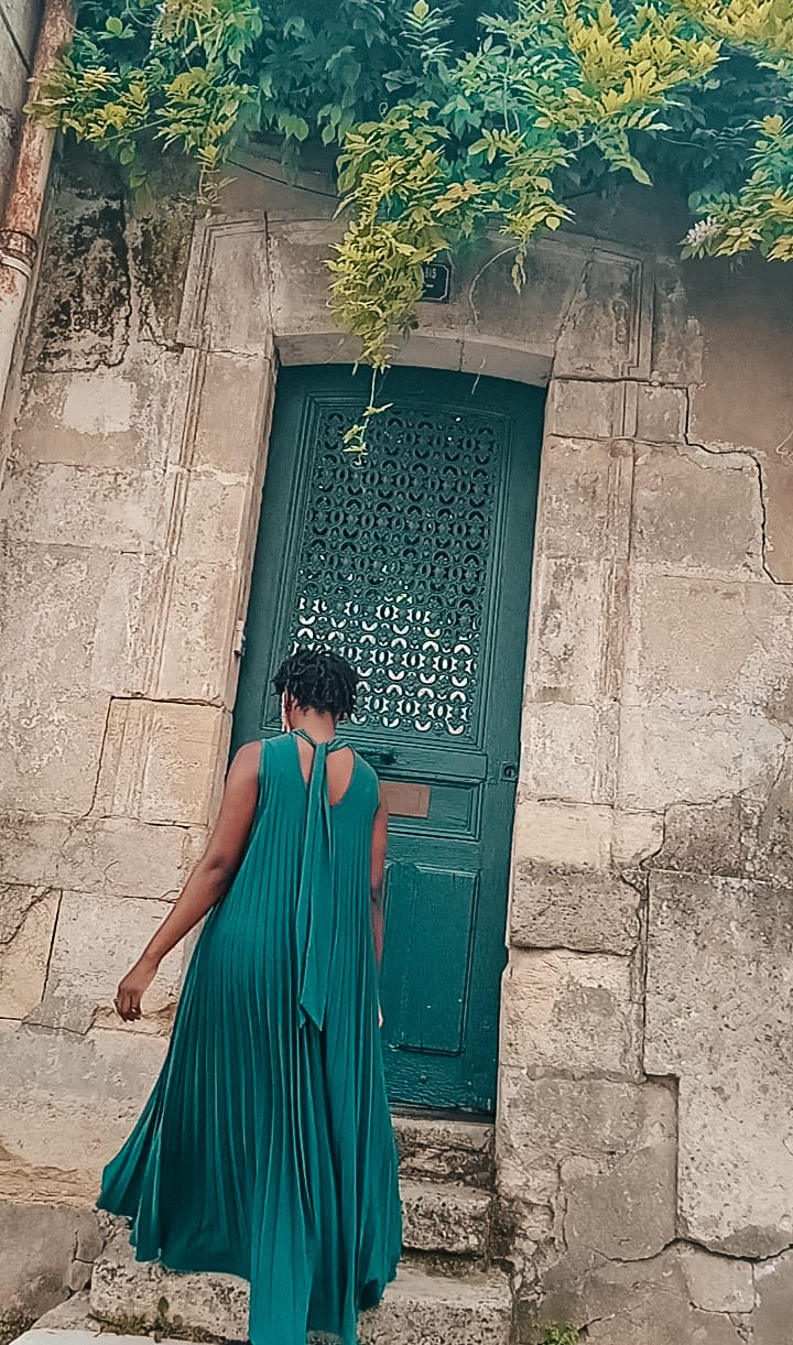 woman turned around wearing gress dress that ties at the back in front of a green door