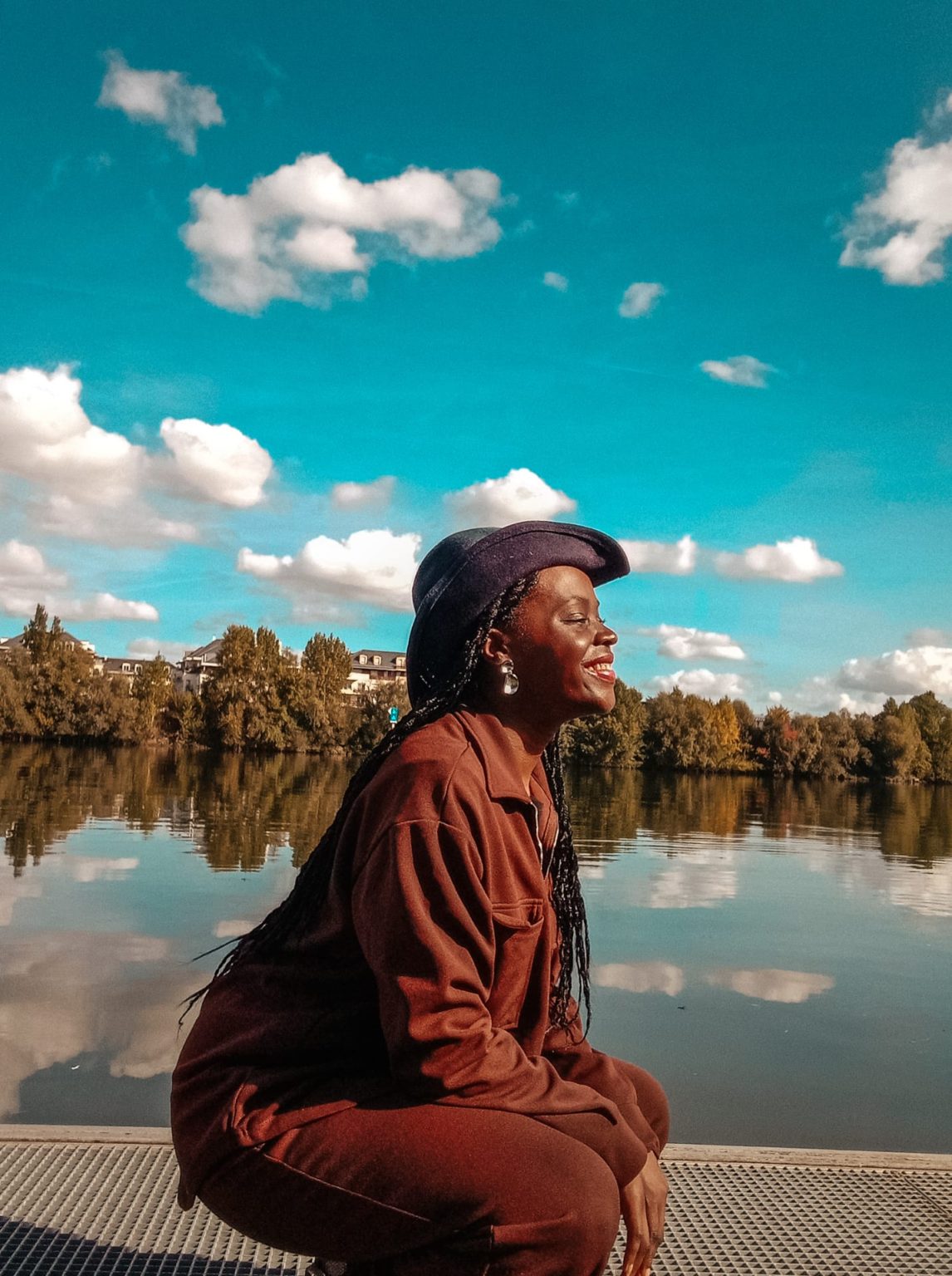 woman sitting by the river. the sly is reflected in the water