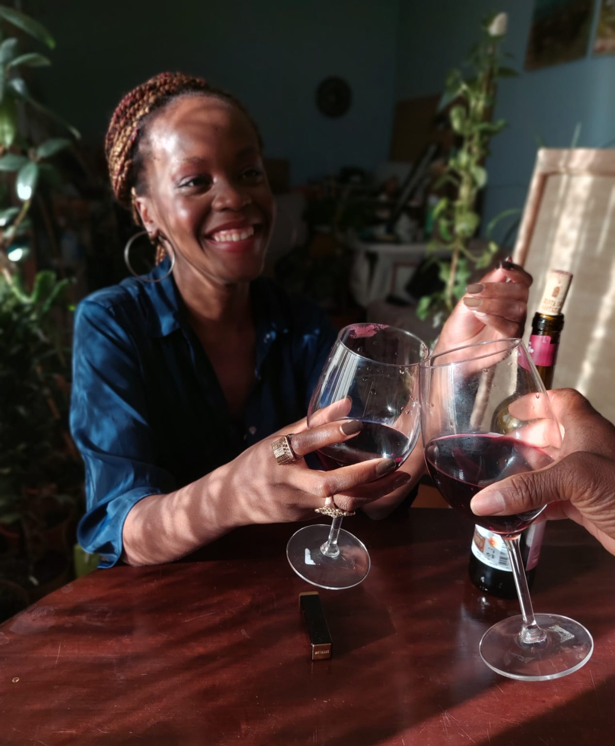two people are making a toast with two glasses of red wine