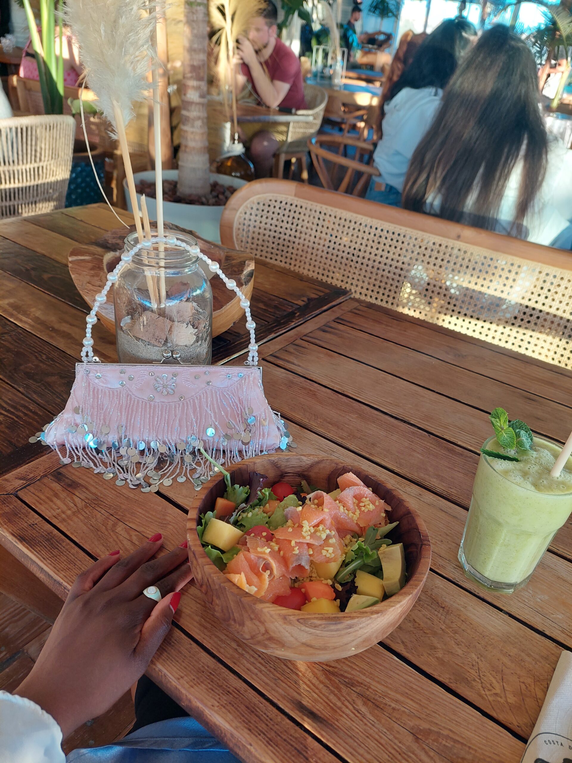 poke bowl, book and bag flatlayed on a wooden table