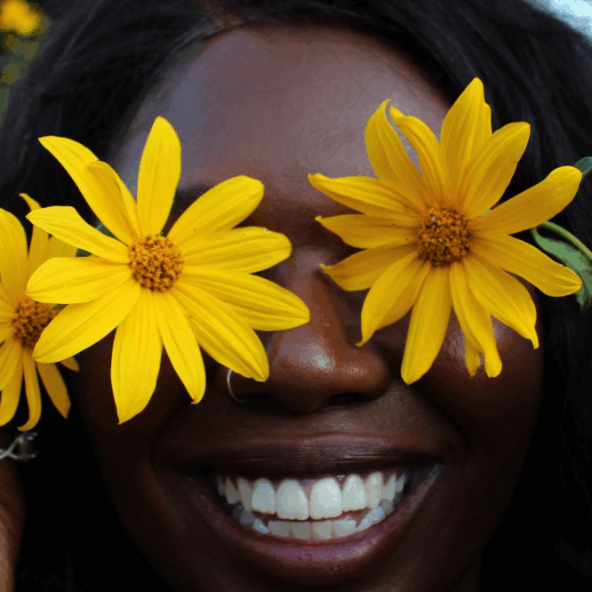 women wears two flowers over her eyes with a big smile. illustrative image from lessons from failure